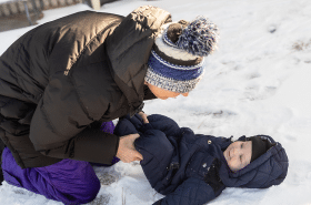 New Horizon Academy infant teacher playing with infant outside in the snow