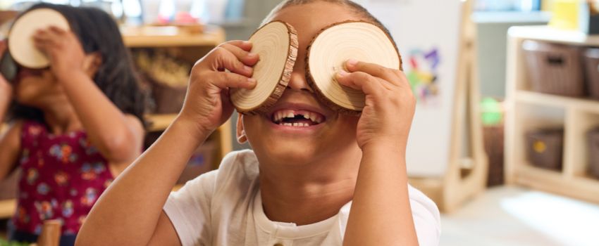 Preschool boy holding up wooden circles as part of classroom "I Spy" activity